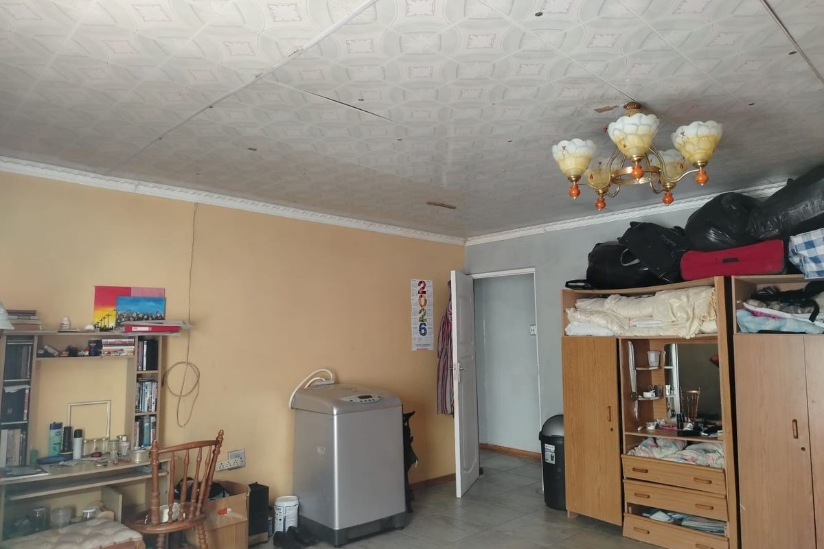 Living area featuring tiled flooring and decorative ceiling tiles, requiring cosmetic updates and repairs to the wall and ceiling finishes.