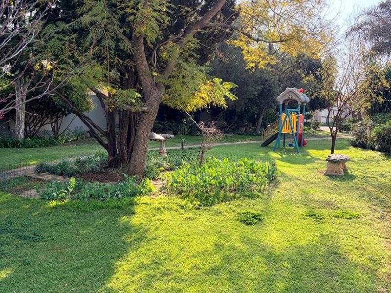 A spacious, well-maintained garden featuring mature trees, established landscaping, and a large lawn area.