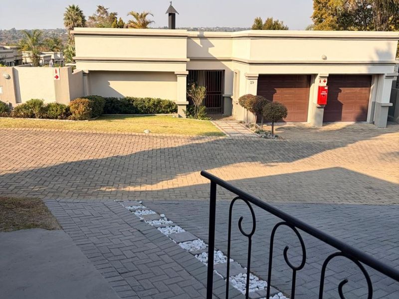 Front view of a modern house featuring a paved driveway, double garage, and a secure gated entrance.