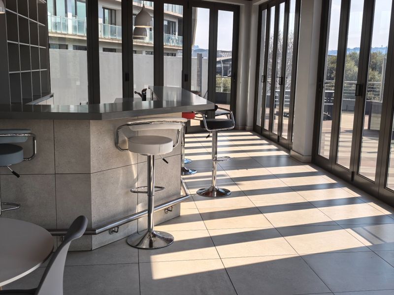 A modern bar area featuring a built-in counter, tiled flooring, and expansive folding glass doors that open to an outdoor space.