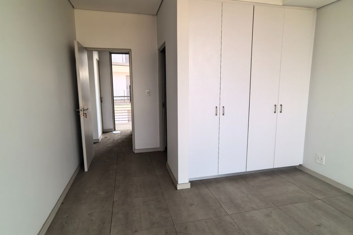 A clean, empty bedroom featuring neutral tiled flooring and ample built-in cupboard storage, offering a blank canvas for personalization.