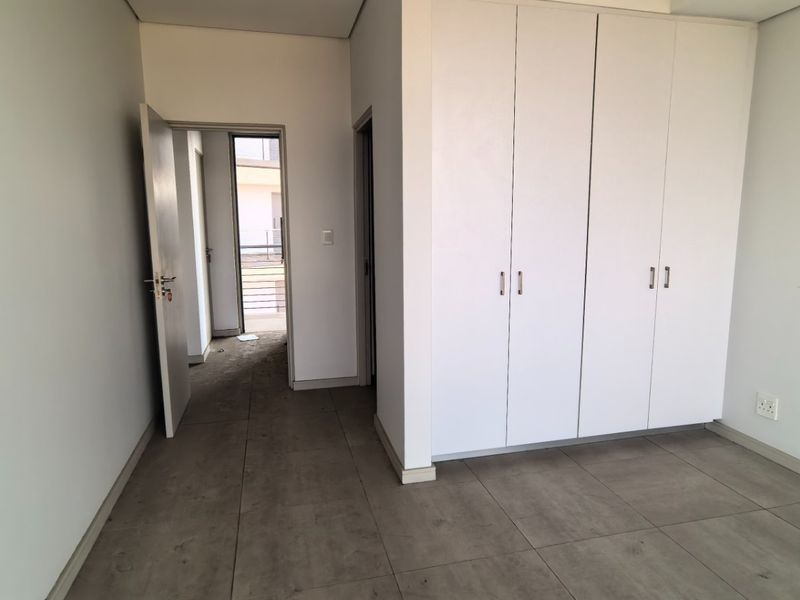 A clean, empty bedroom featuring neutral tiled flooring and ample built-in cupboard storage, offering a blank canvas for personalization.