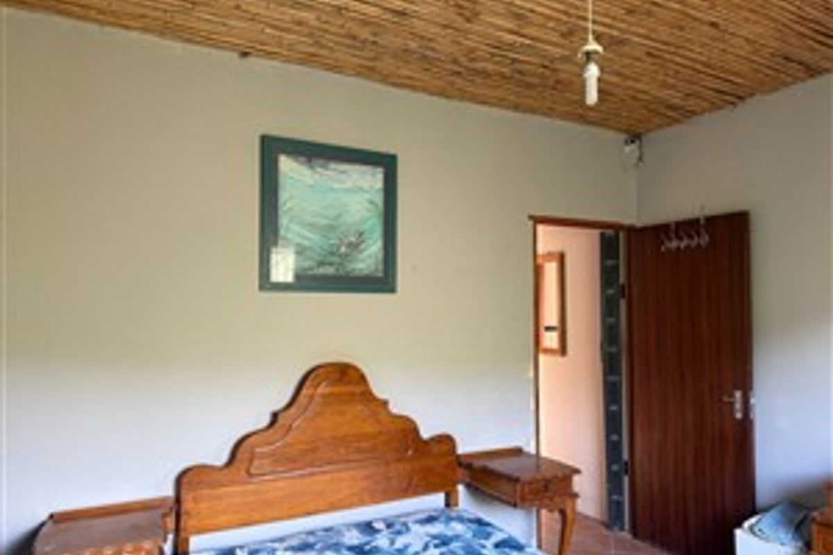 A bedroom featuring a traditional thatched ceiling and a wooden door, offering a rustic aesthetic typical of farm-style architecture.