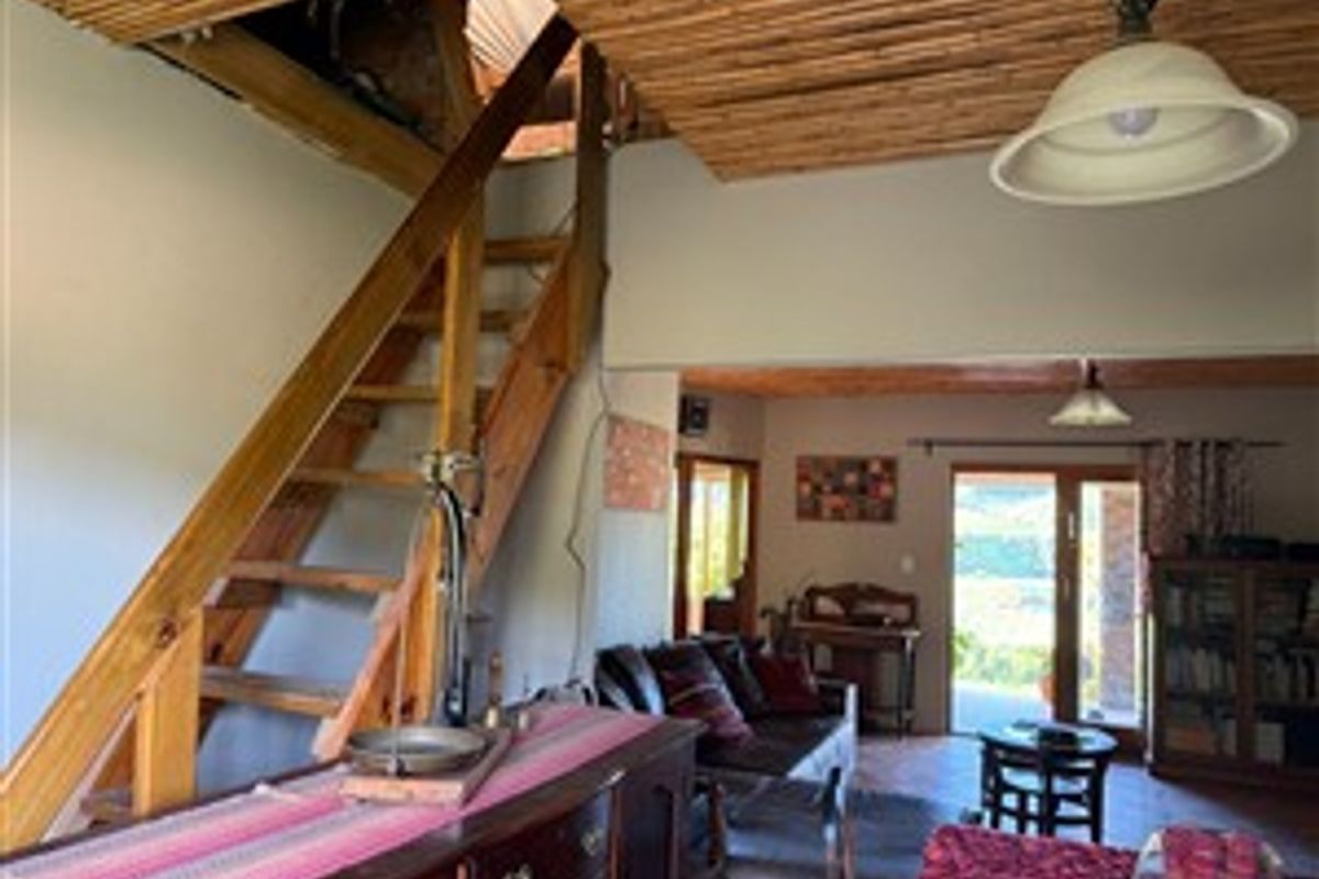 Living area featuring a wooden staircase leading to a loft, exposed reed ceiling, and sliding glass doors providing access to the exterior.