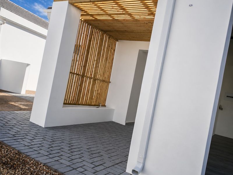 A modern, clean-lined patio area featuring a timber pergola, slat screen, and paved flooring, offering a contemporary outdoor space.