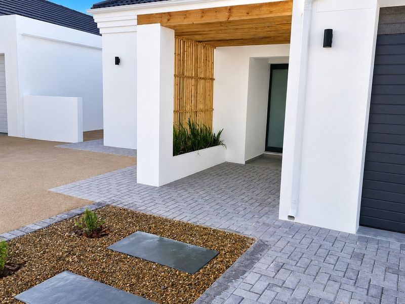 Modern front entrance featuring a paved driveway, timber pergola detail, built-in planter box, and a clean, contemporary facade.