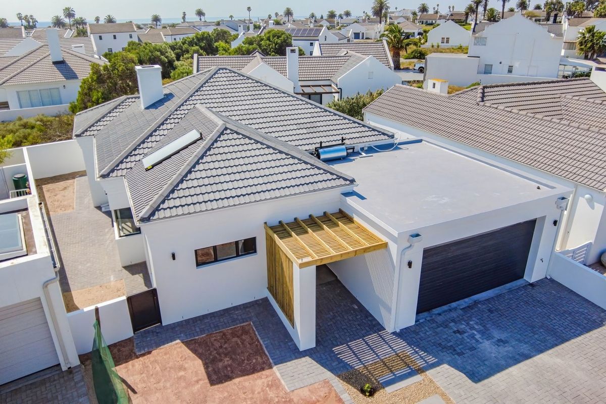 Aerial view of a modern residential property featuring a tiled roof, solar water heating system, timber pergola, and a paved driveway with garage access.
