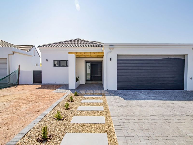 Modern single-story home featuring a paved driveway, automated garage, timber pergola entrance, and a clean, minimalist white facade with established boundary walls.