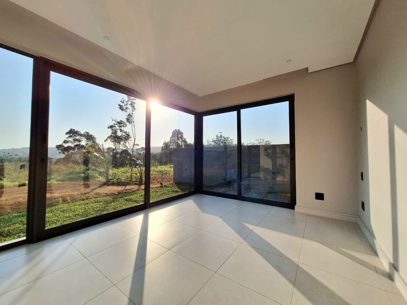 Bright and modern living area featuring expansive corner sliding glass doors that provide seamless indoor-outdoor flow and abundant natural light.