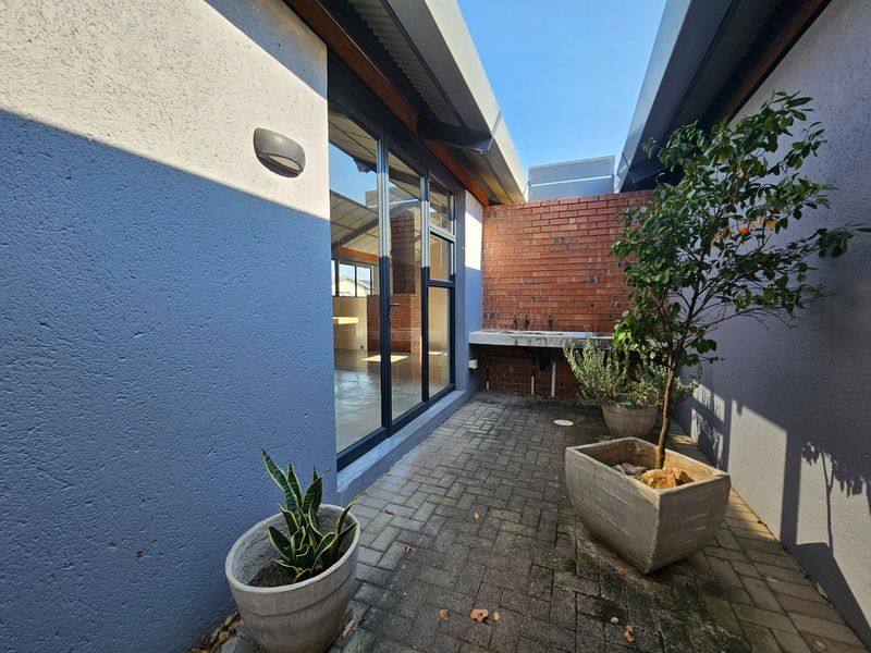 A private outdoor courtyard area featuring paved flooring, a built-in concrete utility sink, and direct access to the interior through glass sliding doors.