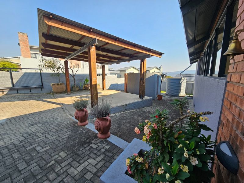 A spacious outdoor patio area featuring a timber pergola, paved flooring, and a water tank, offering a functional space for outdoor living.