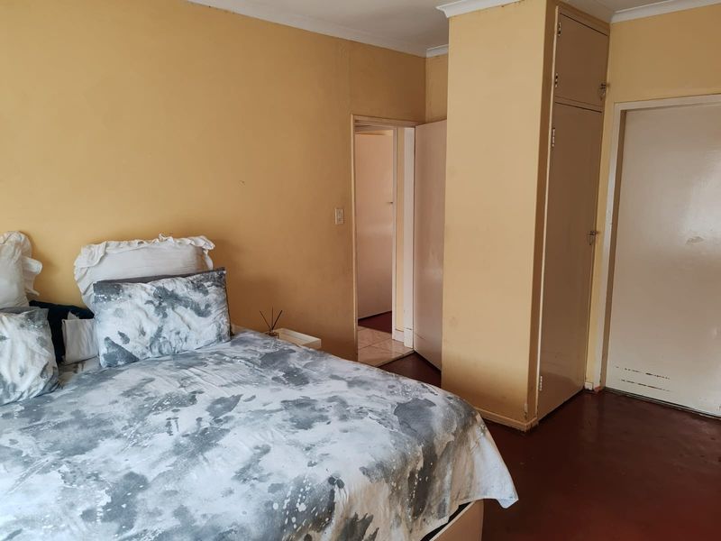 A bedroom featuring built-in cupboards and coving, requiring cosmetic updates to the wall paint and flooring to enhance its appeal.