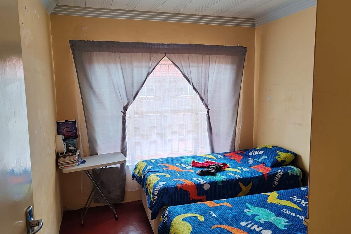A bedroom featuring a panelled ceiling, recessed lighting, and security bars on the window. The room requires cosmetic updates to the wall finishes.