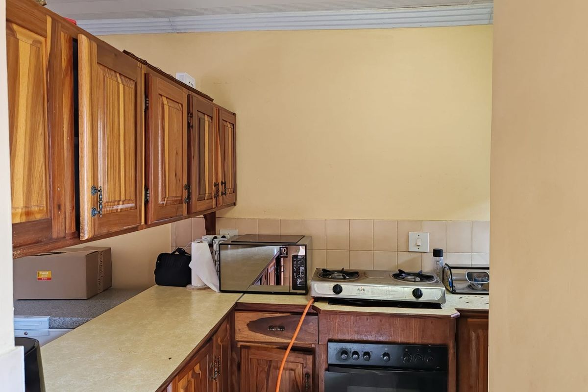A compact kitchen featuring traditional wooden cabinetry, laminate countertops, a built-in oven, and a gas hob with tiled splashback.