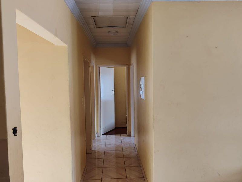 A vacant interior hallway featuring tiled flooring, ceiling coving, and access to adjacent rooms.