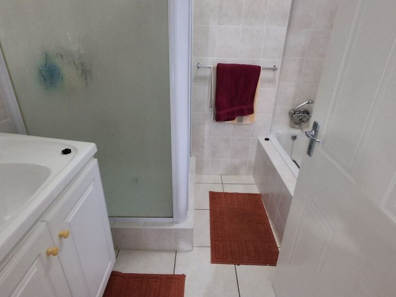 A functional bathroom featuring a vanity basin, a separate shower enclosure, and a bathtub with tiled finishes throughout.