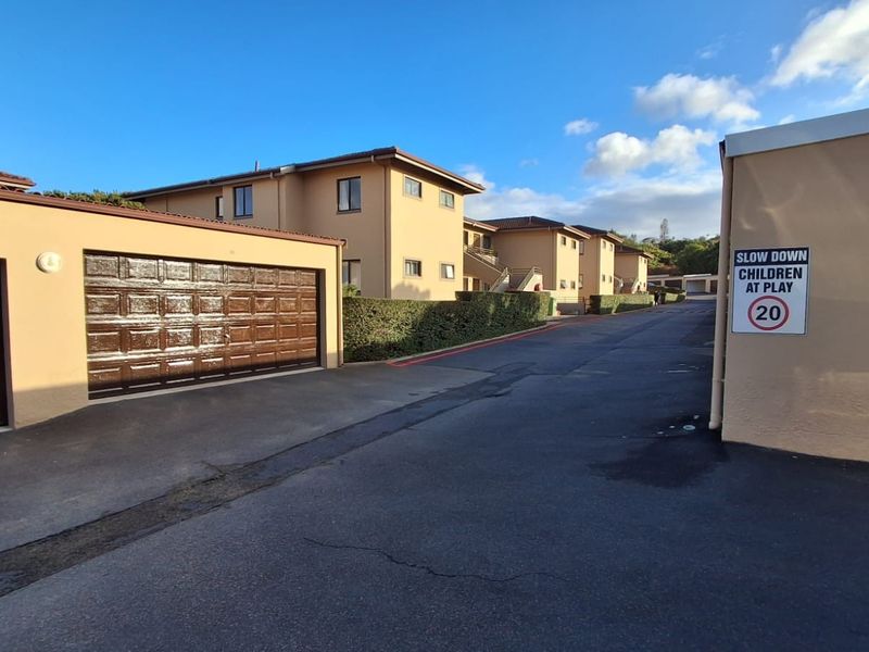 A view of the complex driveway featuring multiple garage units and residential building facades with paved access.