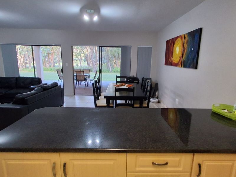 Open-plan living and dining area featuring a kitchen with granite countertops and large sliding doors leading to an outdoor patio space.