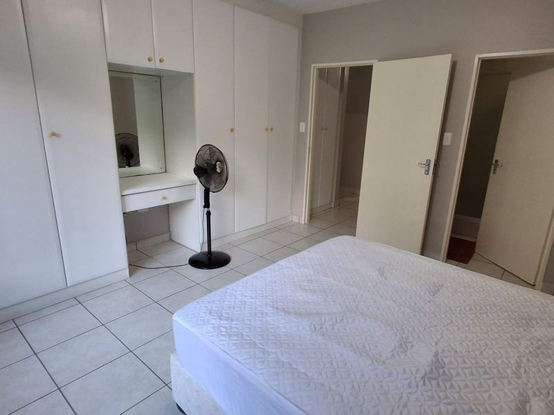 Bedroom featuring extensive built-in cupboards with an integrated vanity area and neutral tiled flooring.