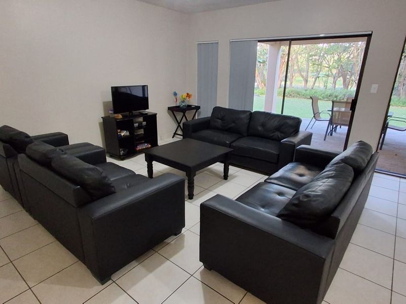 Spacious living room featuring neutral tiled flooring and large sliding glass doors that provide direct access to the outdoor patio and garden area.