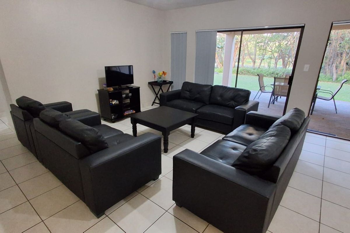 Spacious living room featuring neutral tiled flooring and large sliding glass doors that provide direct access to the outdoor patio and garden area.