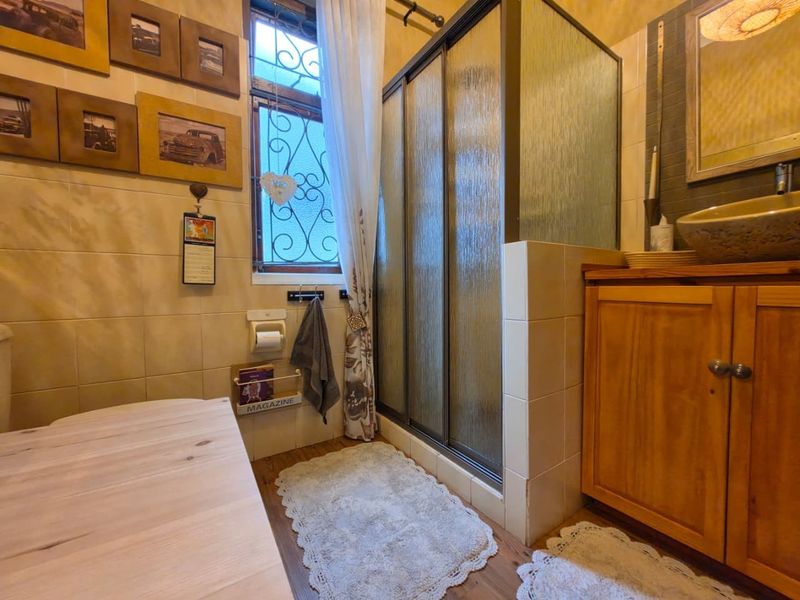A bathroom featuring a shower enclosure, a wooden vanity cabinet with a vessel sink, and tiled wall finishes.