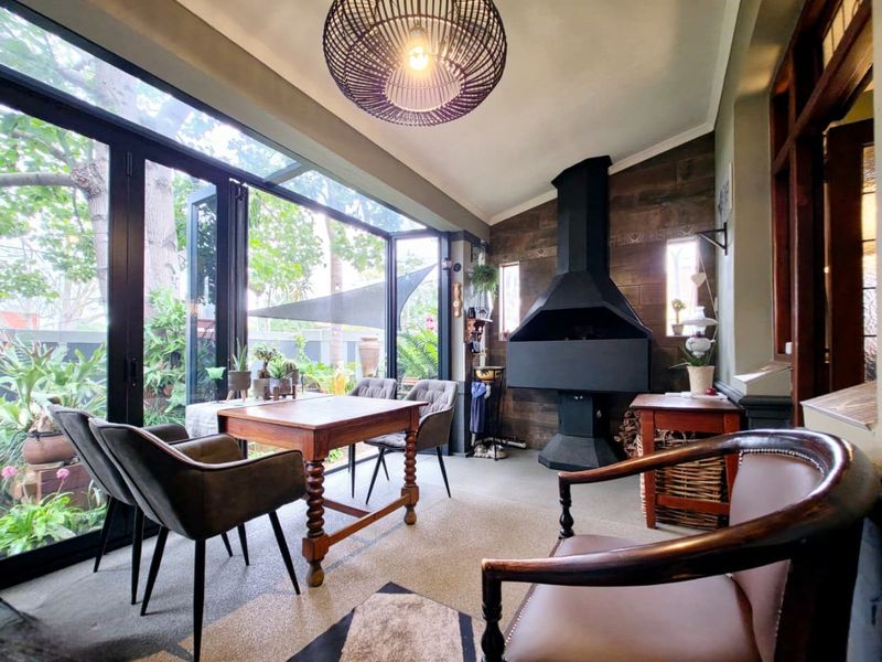 A bright, enclosed patio featuring a built-in fireplace, large bi-fold glass doors, and textured wall finishes, creating a seamless indoor-outdoor living space.