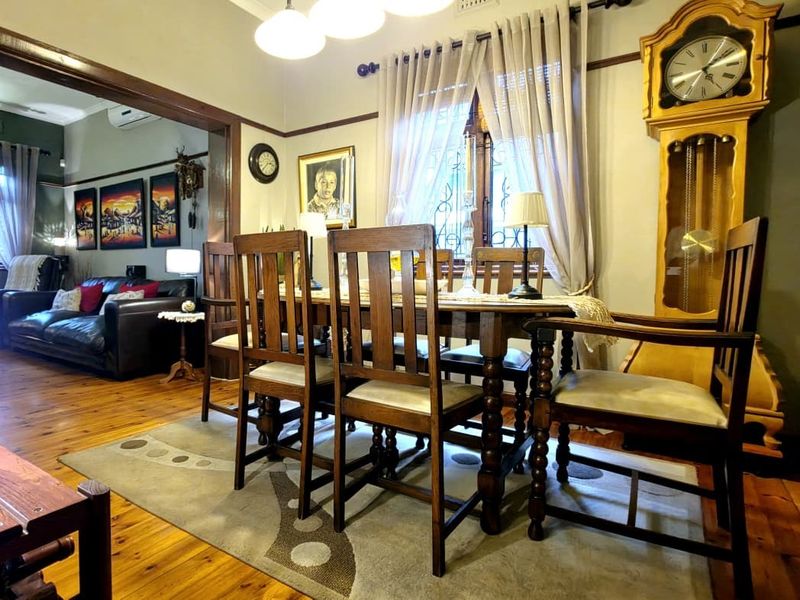 A traditional dining room featuring polished timber flooring, classic picture rails, and coved cornices, seamlessly flowing into the adjacent living area.