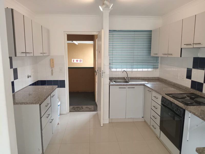 Functional kitchen featuring white cabinetry, granite countertops, built-in oven and hob, tiled backsplash, and tiled flooring.