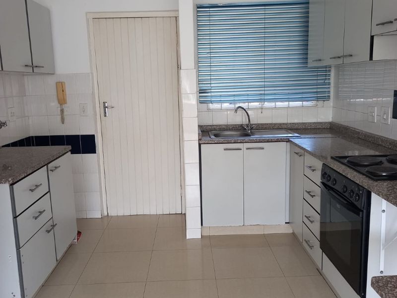 A functional kitchen featuring built-in cabinetry, granite countertops, a built-in oven with hob, and tiled flooring, offering a clean and practical workspace.