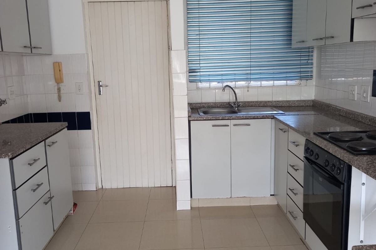 A functional kitchen featuring built-in cabinetry, granite countertops, a built-in oven with hob, and tiled flooring, offering a clean and practical workspace.