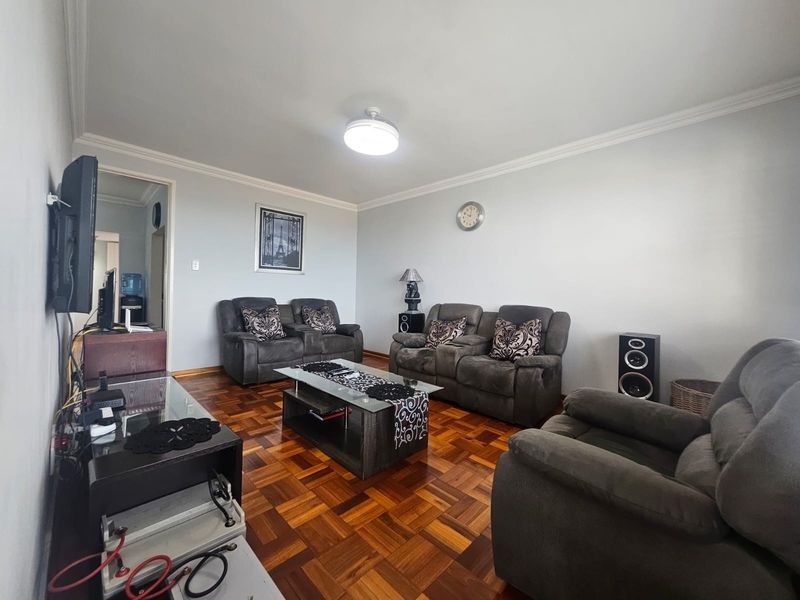A spacious living room featuring classic parquet flooring and decorative ceiling cornicing, providing a solid foundation for modern interior updates.