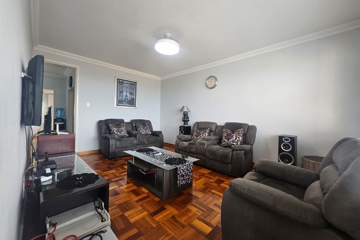 A spacious living room featuring classic parquet flooring and decorative ceiling cornicing, providing a solid foundation for modern interior updates.