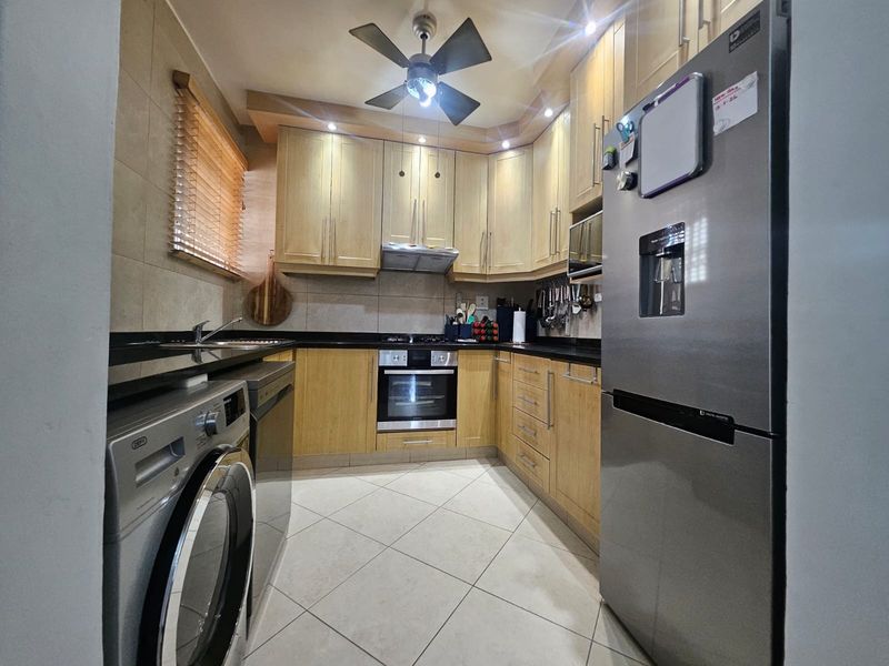 A well-maintained kitchen featuring light wood cabinetry, granite countertops, integrated appliances, and tiled flooring, offering a functional and organized cooking space.