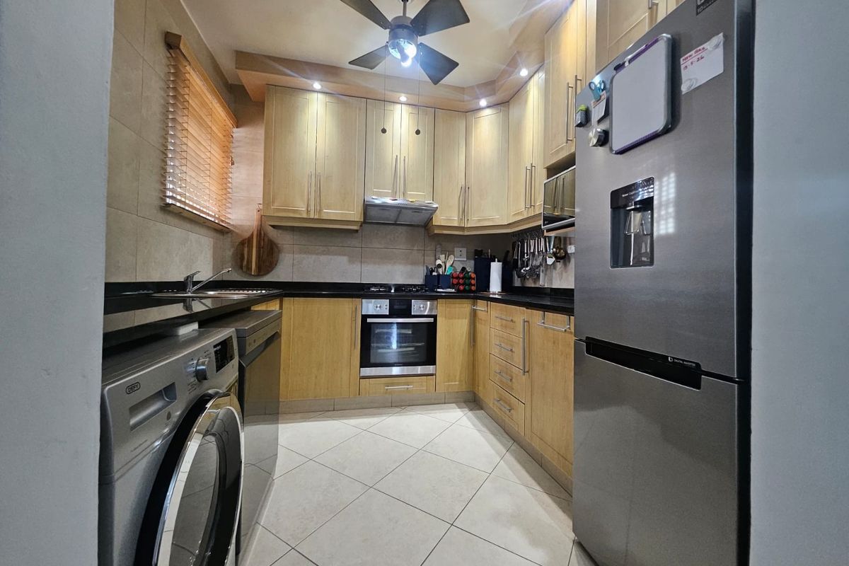 A well-maintained kitchen featuring light wood cabinetry, granite countertops, integrated appliances, and tiled flooring, offering a functional and organized cooking space.