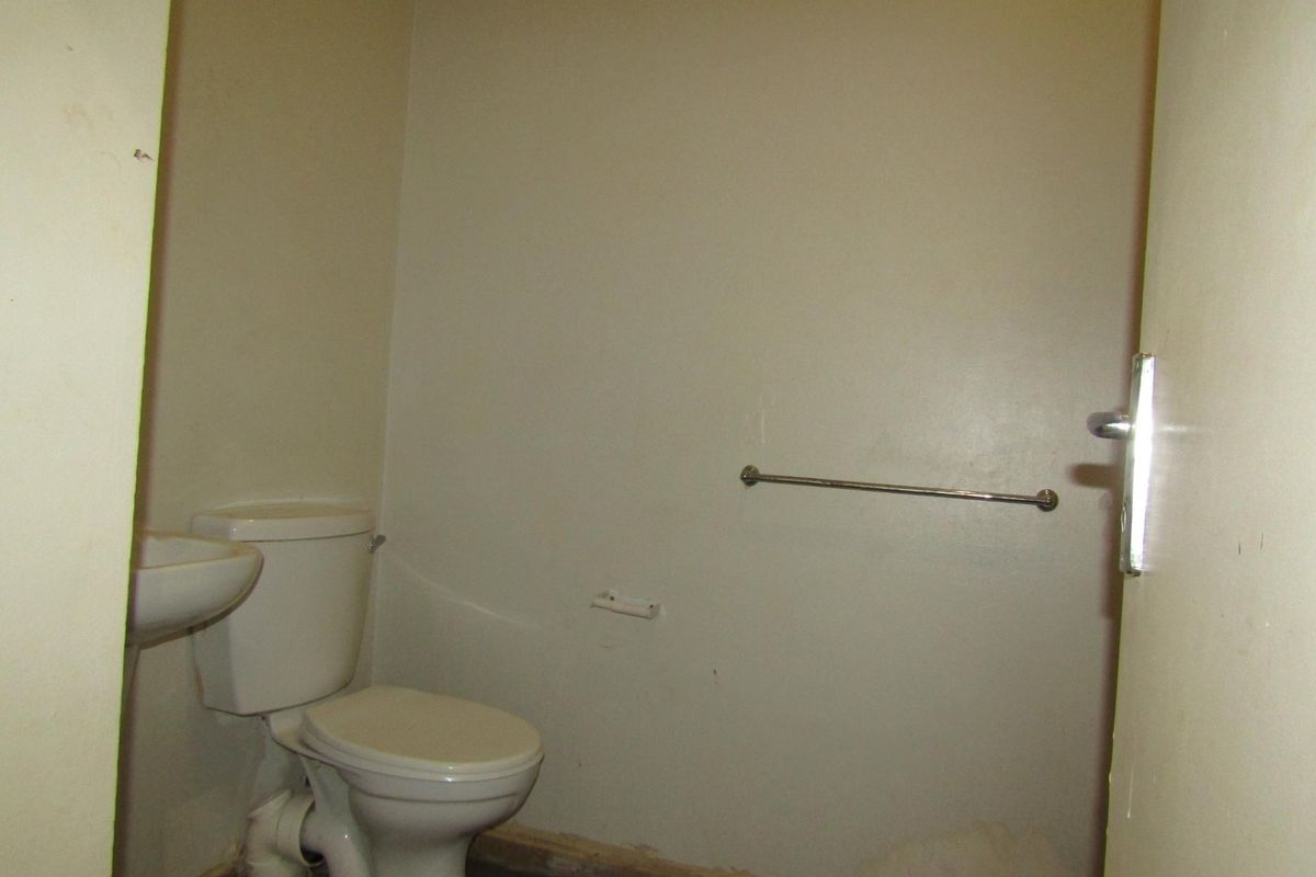 A small, empty bathroom featuring a standard toilet and pedestal basin, requiring cosmetic updates and repairs to the wall finishes and skirting.
