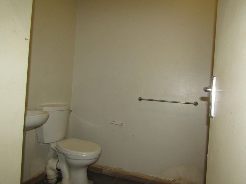 A small, empty bathroom featuring a standard toilet and pedestal basin, requiring cosmetic updates and repairs to the wall finishes and skirting.