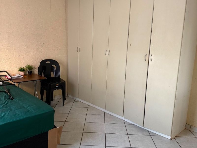 Bedroom featuring built-in cupboards, a ceiling fan, and tiled flooring. The space offers functional storage and basic finishes.