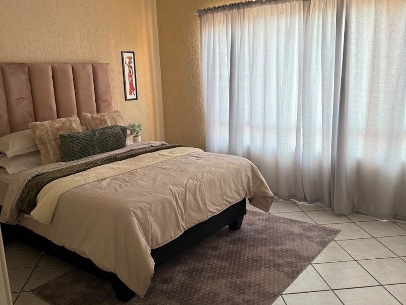 A bedroom featuring tiled flooring, a ceiling fan, and textured walls, offering a neutral base for personalization.