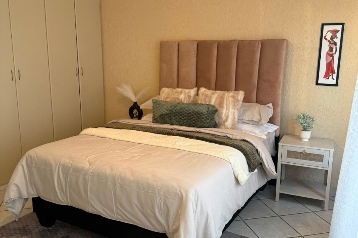 A bedroom featuring tiled flooring, built-in cupboards for storage, and a ceiling fan.