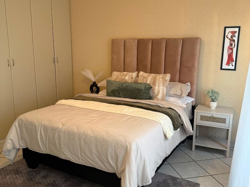 A bedroom featuring tiled flooring, built-in cupboards for storage, and a ceiling fan.