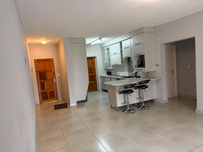 Open plan kitchen area featuring built-in cabinetry, a breakfast bar, and tiled flooring, seamlessly connecting to the main living space.