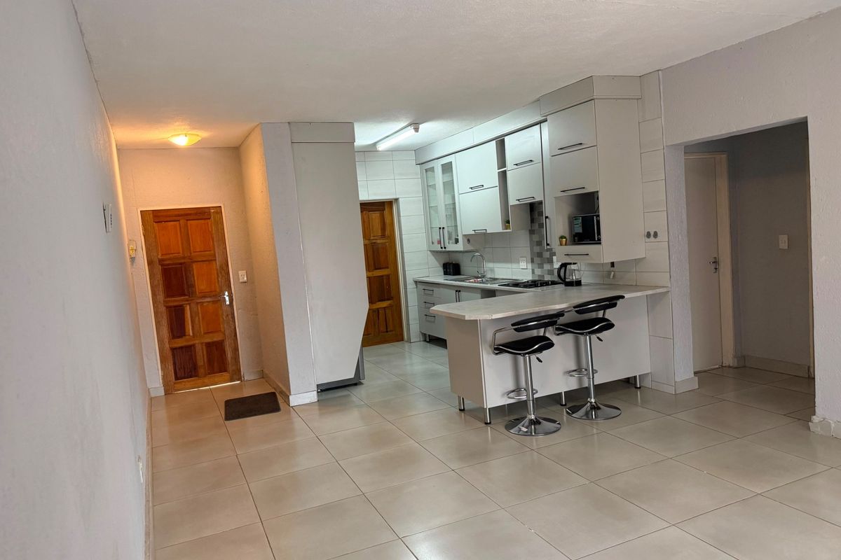 Open plan kitchen area featuring built-in cabinetry, a breakfast bar, and tiled flooring, seamlessly connecting to the main living space.