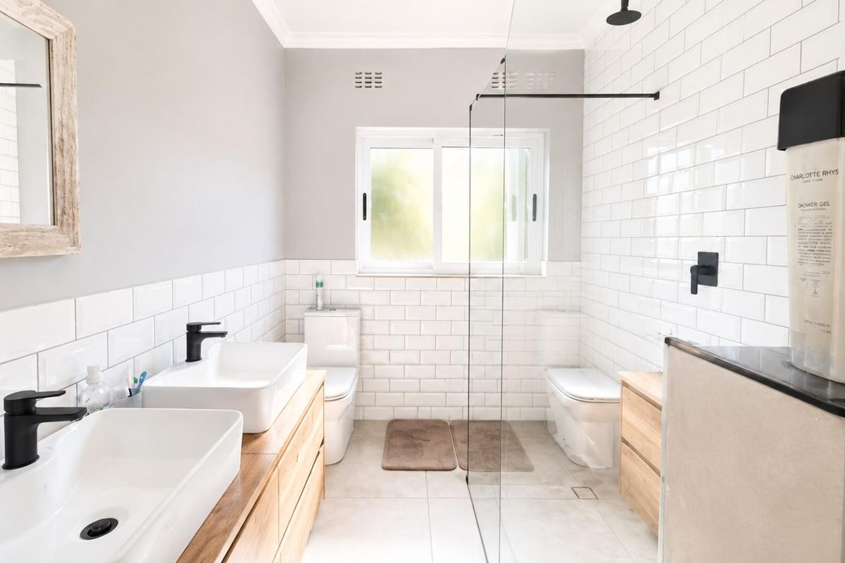 Modern bathroom featuring a double vanity with vessel sinks, black matte fixtures, and a spacious walk-in shower with subway tile finishes.