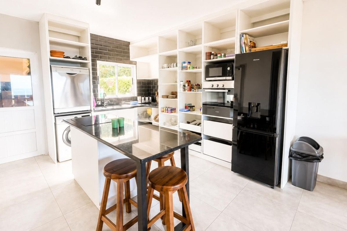 Modern kitchen featuring extensive built-in shelving, black granite countertops, subway tile backsplash, and integrated appliances, offering a clean and functional culinary space.