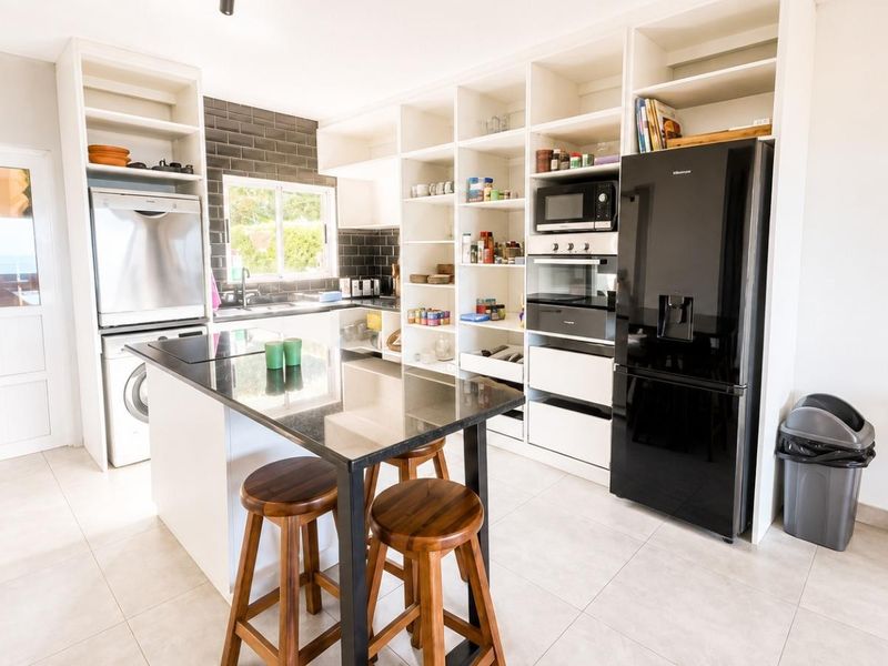 Modern kitchen featuring extensive built-in shelving, black granite countertops, subway tile backsplash, and integrated appliances, offering a clean and functional culinary space.