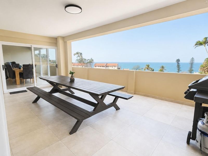 Spacious covered balcony featuring tiled flooring, solid balustrades, and expansive ocean views, providing an ideal outdoor entertainment space.