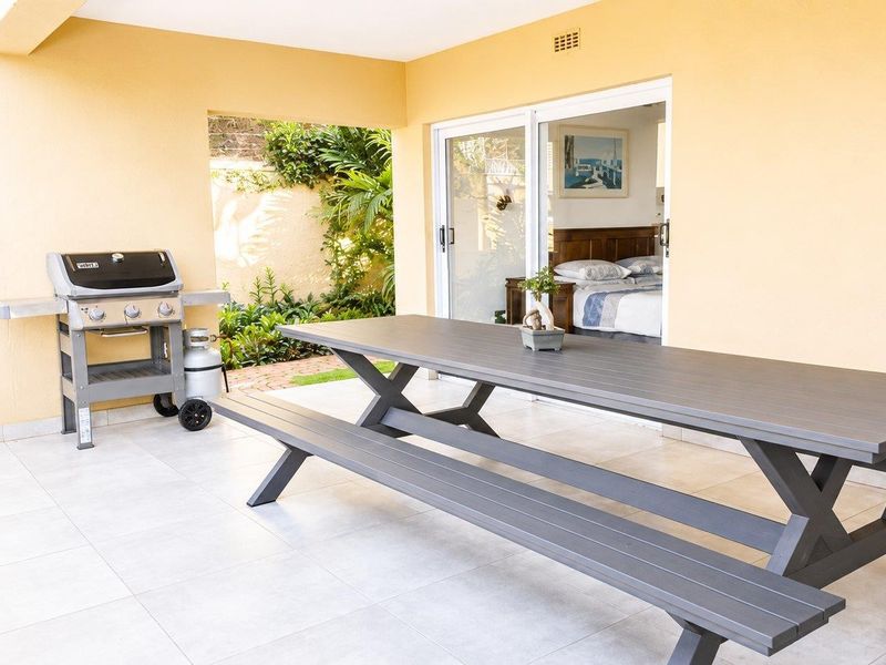 A covered outdoor patio featuring tiled flooring and sliding glass door access to the interior bedroom.