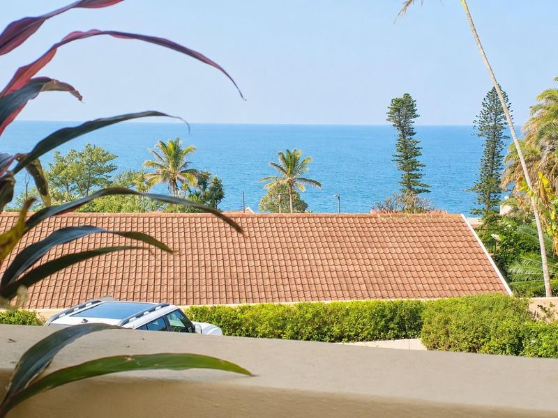 A scenic elevated view of the ocean and surrounding coastal landscape captured from a balcony.