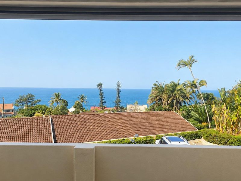 A clear, elevated ocean view captured from a balcony, showcasing the surrounding coastal landscape and residential neighborhood.